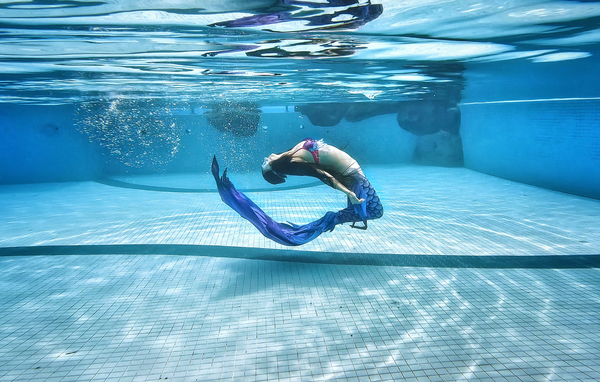 Student arching backwards in a mermaid tail during a PADI mermaid course in Kuala Lumpur